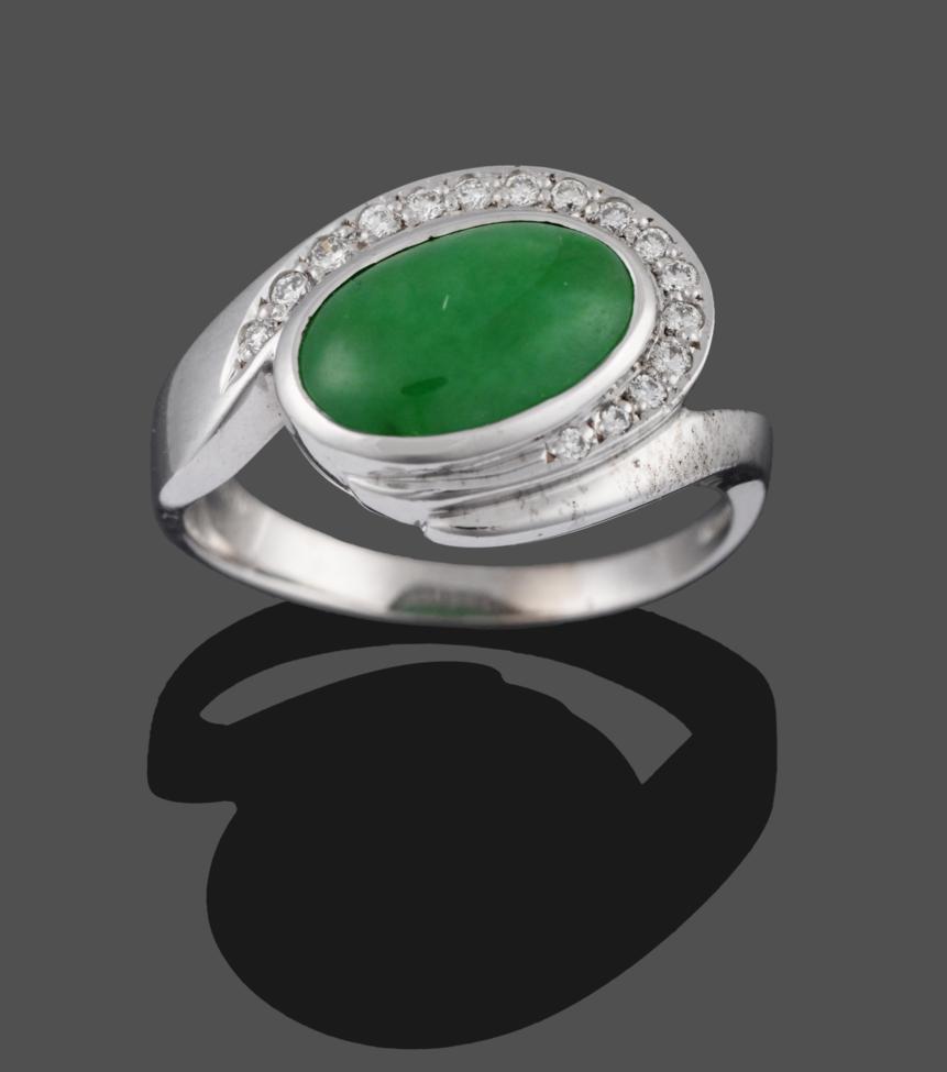 An 18 Carat White Gold Jade and Diamond Ring, an oval cabochon jade in a collet setting with a row