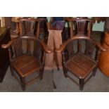 A pair of George III style oak elbow chairs with solid seats