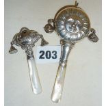 Two hallmarked silver baby rattles with mother of pearl handles. One with legend "Baby", the other