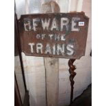 Original cast iron railway sign "BEWARE OF THE TRAINS" on painted wooden post, originally from the