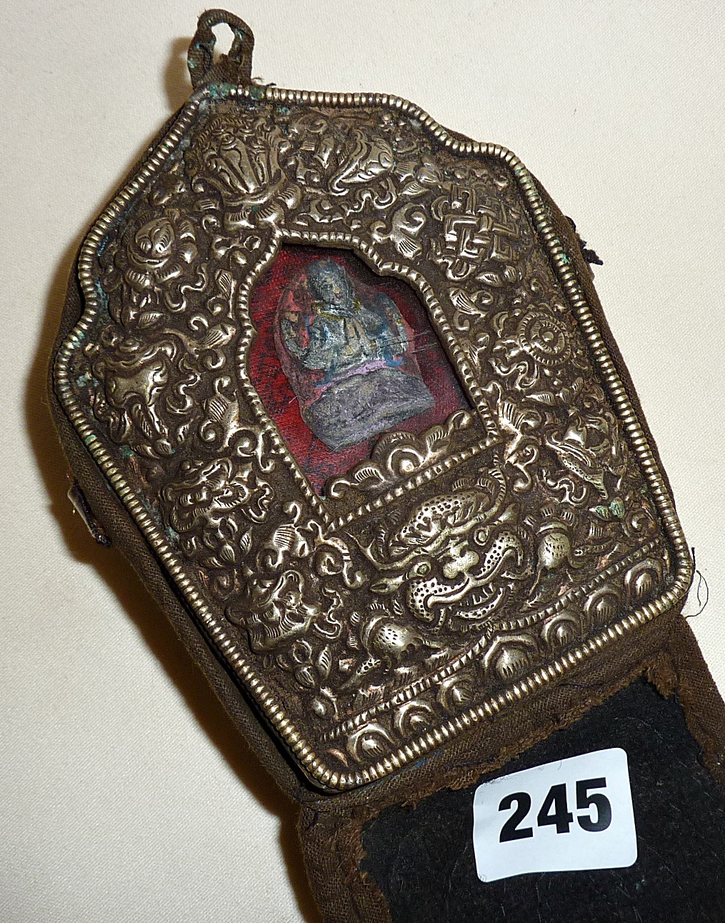 An antique Tibetan silver fronted copper backed Gau travelling Buddhist prayer shrine in a silk