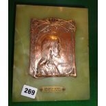 A Salvatore Mundi Arts & Crafts repoussé copper plaque depicting Christ mounted on a brass backed