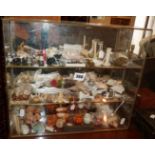 Three tier glass table cabinet with large quantity of assorted small ornaments and novelties