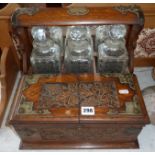 Victorian brass-bound carved oak tantalus, having three decanters and lockable compartment for