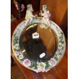 A Sitzendorf porcelain oval mirror encrusted with flowers and having two cherubs to top