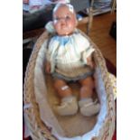 A doll by A-S, Germany in a wicker cradle