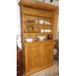 Stripped pine dresser of three shelves above two panelled cupboard doors