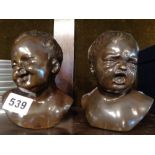Two bronze busts of babies or young children, one laughing one crying