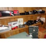 Three shelves of assorted cameras and projectors etc