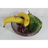 A silver plated bowl containing ceramic models of fruit and vegatables