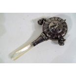 A silver hallmarked rattle decorating style depicting the sun,