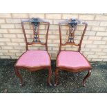 A matched pair of mahogany dining chairs with red upholstered seats.