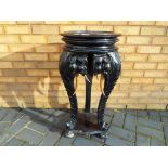 A highly carved ebonised occasional elephant table with the top raised on three elephant trunk