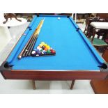 A pool table with folding legs, four pool cues,