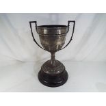A vintage twin handled trophy with foliate decoration on an ebonised base engraved Barker Challenge