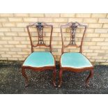 A matched pair of mahogany dining chairs with green upholstered seats.