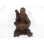 An Oriental hardwood carving depicting a seated Buddha having glass eyes,