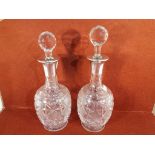 A pair of cut glass decanters with silver collars,