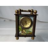 A miniature brass mantel clock with panel scenes.