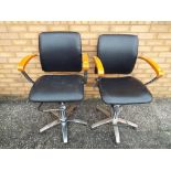 Two retro black wood and chrome finish barber's chairs with swivel movement and pump fitted with
