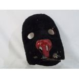 A vintage theatrical prop/mask depicting a cat, with fur lined exterior, metal teeth,