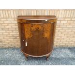 A walnut veneered half moon side cabinet, raised on four claw feet supports,