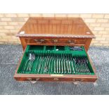 A mahogany, three drawer, free standing canteen of cutlery with a quantity of plated flatware,