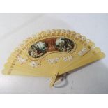 A vintage painted hand fan with floral edging and gilded highlights with ribbon attachment