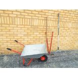 A metal wheelbarrow and a small quantity of garden tools to include a rake,