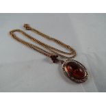 A 9ct gold necklace with 9ct gold pendant set with large amber centre stone surrounded by a stone