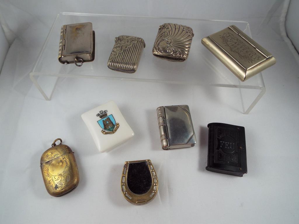 A collection of nine white and yellow metal vestas and snuff boxes and similar