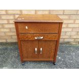 An oak sewing cabinet with twin door cupboard and single drawer on four castors approx 66cm x 51cm