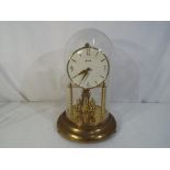 An Anniversary clock under glass dome, dial marked Bentima, Arabic numerals to a white dial.