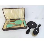 An enamelled dressing table set contained in original case comprising hand mirror, brushes,