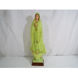 A glow in the dark religious figurine on wooden plinth, approximately 54 cm (h).