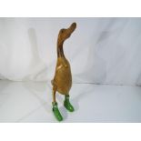 A wooden figurine of a duck wearing green Hunter wellies,