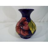 Moorcroft Pottery - a medium sized Moorcroft Pottery bulbous vase decorated with hibiscus on a blue