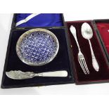 A presentation case displaying a George V glass and silver rimmed butter hold set with Mother of