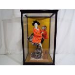 A good quality figurine depicting a Geisha in traditional dress holding a taiko contained in a