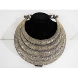 A large white metal five section necklace with repousse decoration