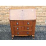 A slope fronted bureau with a pigeon hole interior with faux leather writing desk over three