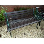 A Victorian style two seat garden bench with weathered timber lathes raised on a pair of decorative