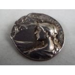 A 1940's white metal brooch, depicting a lady, looking at bats across the water under stylite,