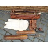 A vintage cricket bag containing a quantity of related items, including stud wickets, cricket bats,