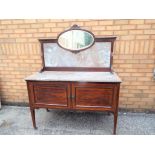 A marble topped wash stand with marble back supporting a small oval mirror,
