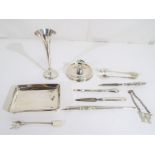 A collection of silver items to include a trumpet vase, sugar tongs, bottle label,