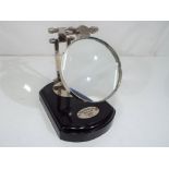 A chrome magnifying glass on a wooden ba