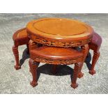 A decoratively carved circular coffee table with four nesting stools,