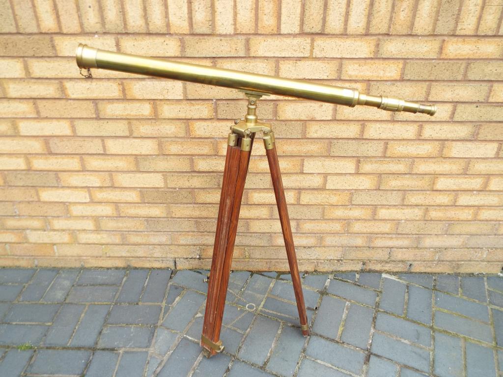 A large brass telescope on adjustable wood and brass tripod support,