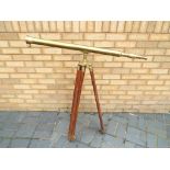 A large brass telescope on adjustable wood and brass tripod support,